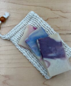 Three sample pieces of soap laying on a sisal soap saver.